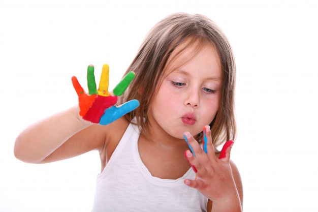 A young girl with her hands painted in bright colours, palms spread out