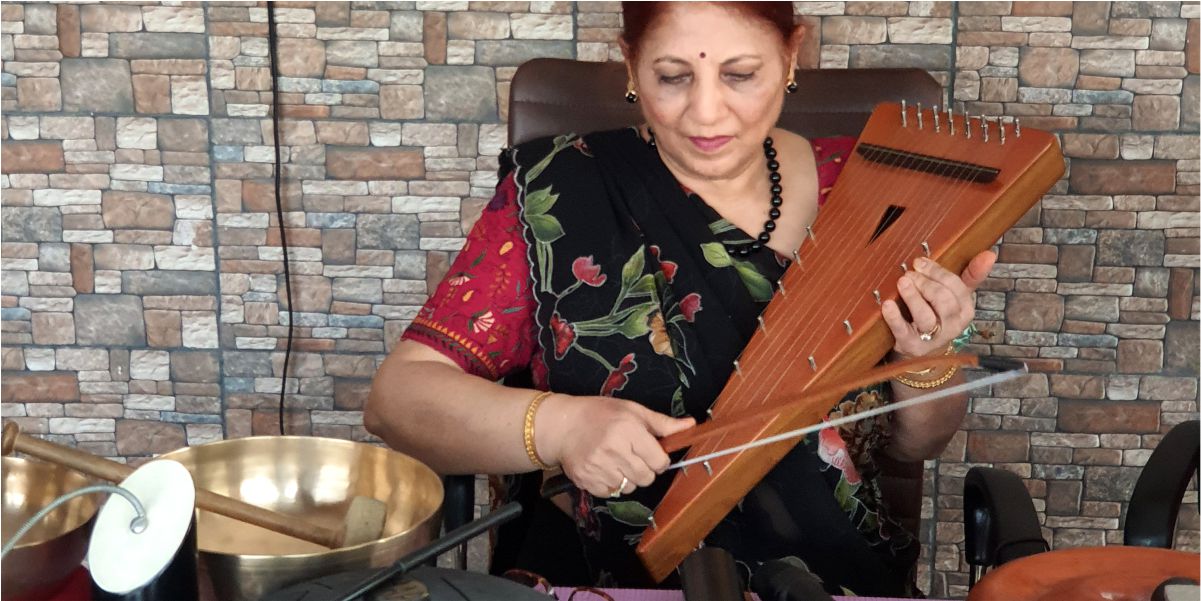 A music therapy practitioner at SFCT playing a bowed string instrument, with a Tibetan singing bowl and mallet visible beside her.